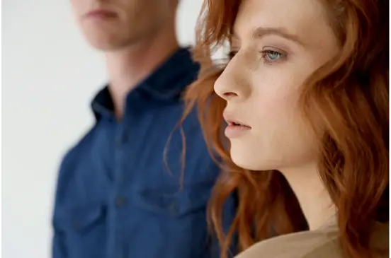 woman with red hair and man standing in background