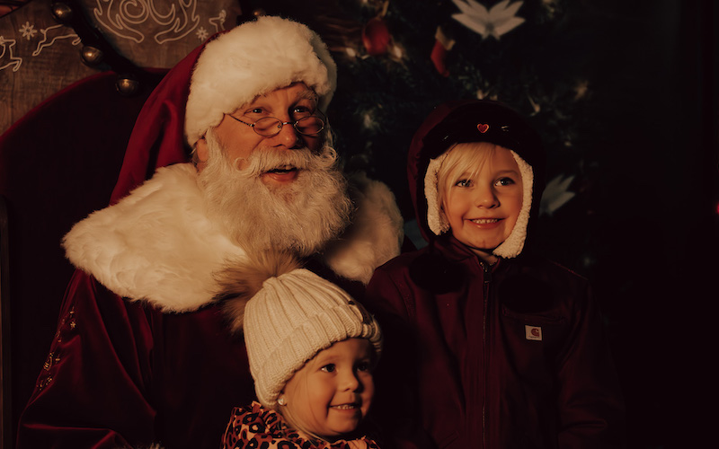 Santa posing with two small children dressed for winter